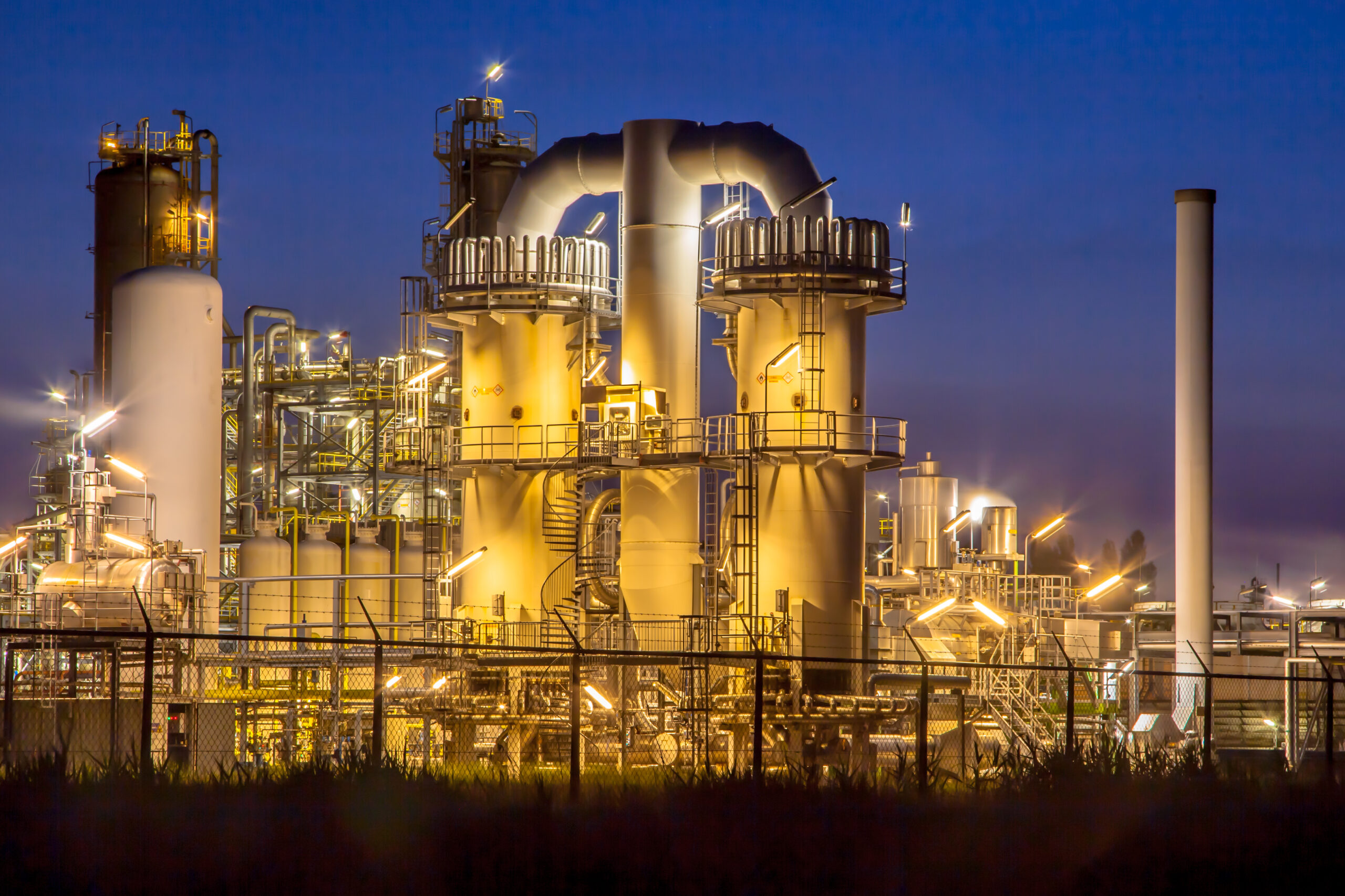 Detail of a heavy Chemical Industrial plant with mazework of pipes in twilight night scene